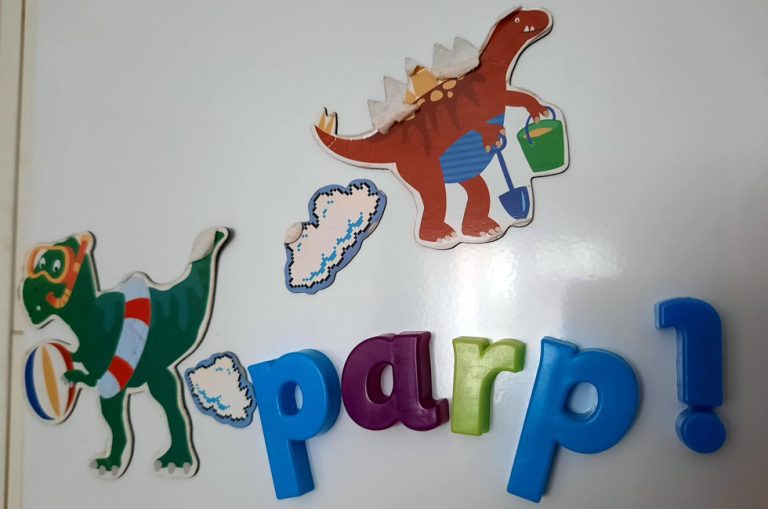 Some children's fridge magnets showing two cartoon dinosaurs with clouds positioned under their tails and the word "parp!" written in colourful letters.